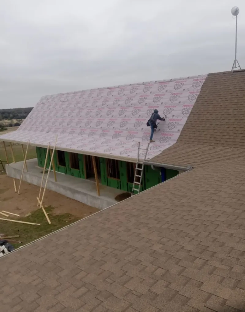 Worker preparing underlayment for a metal roof installation in Steiner Ranch